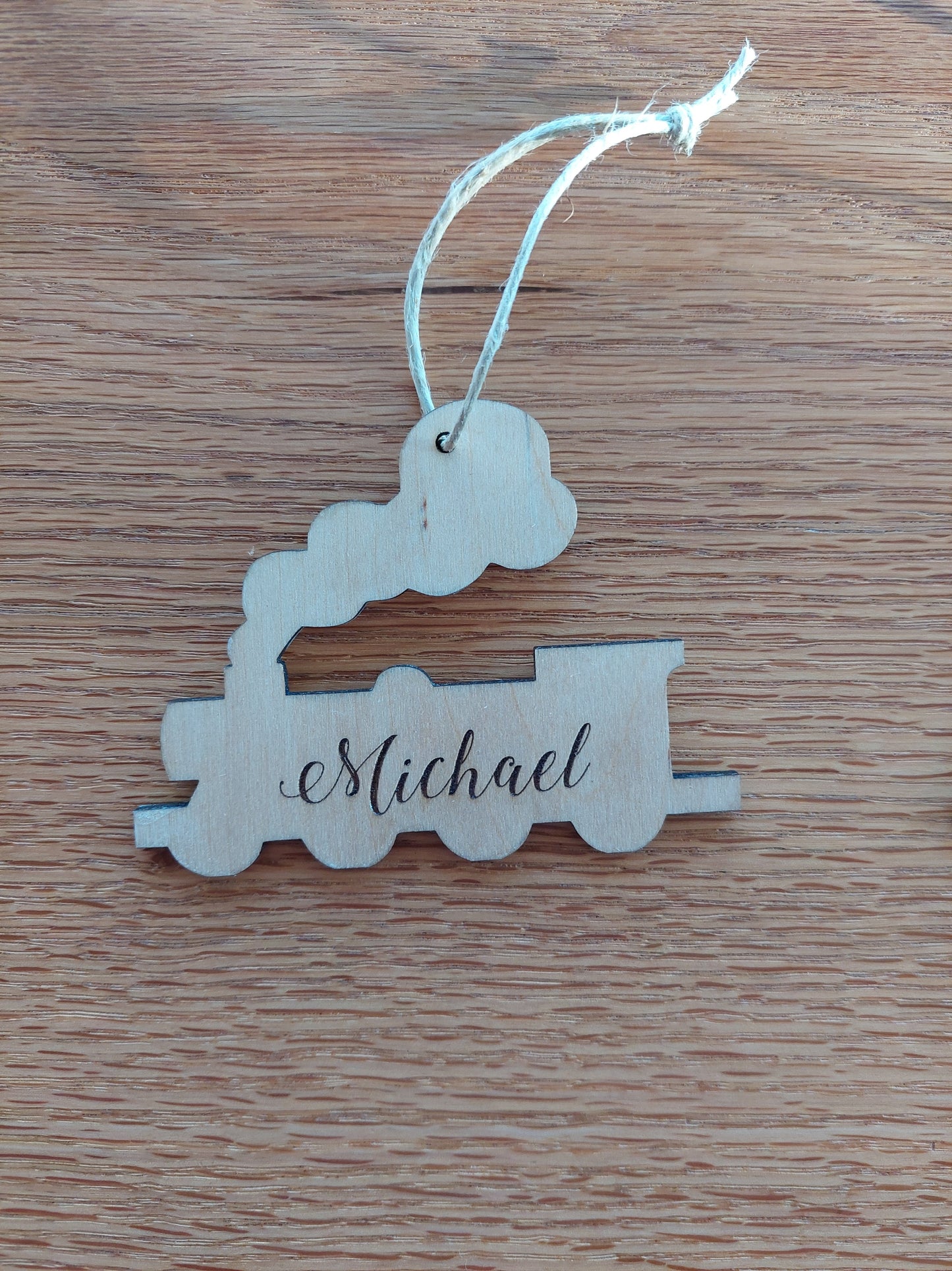 Engraved wooden train Christmas ornament made of birch wood with red ribbon, personalized for kids or train lovers.