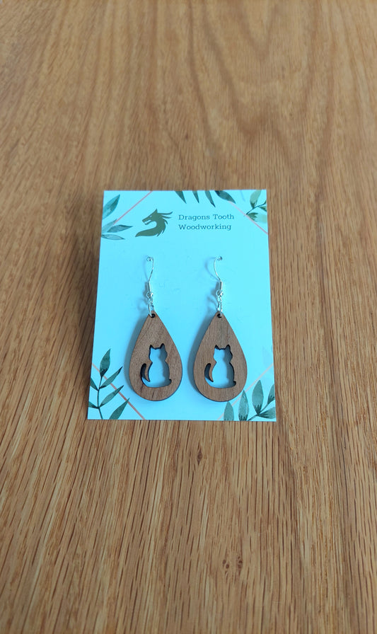 A front view of the circular cat silhouette earrings crafted from warm, traditional caramel-toned solid Cherry wood, displayed on an earring card.