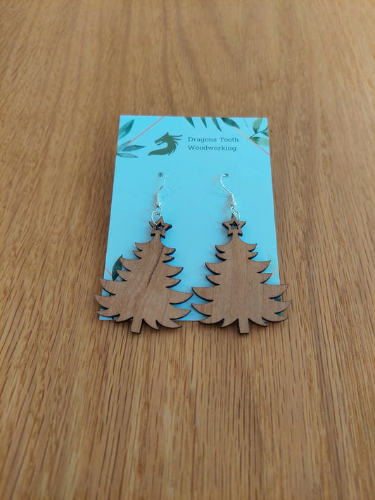 A front view of the Christmas tree earrings crafted from warm, traditional caramel-toned solid Cherry wood, displayed on an earring card.