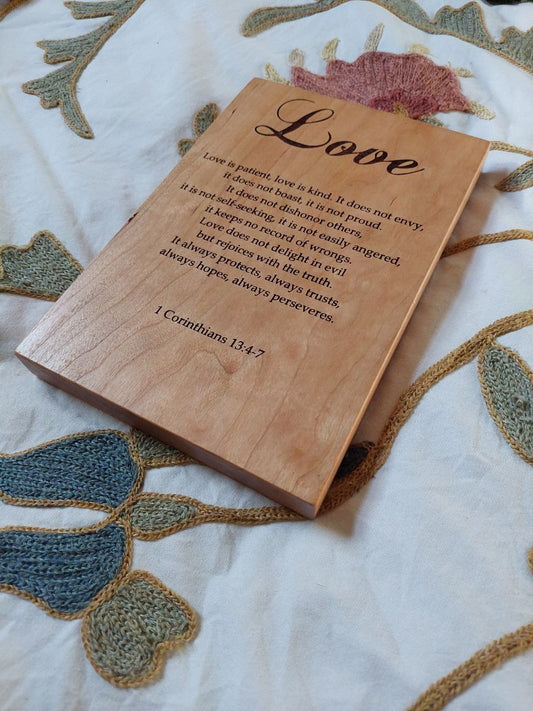 Angled close-up showing the deep, precise engraving details on a cherry wood Love Chapter plaque.