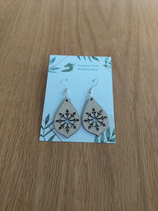 A front view of the large snowflake teardrop earrings crafted from light, bright blonde solid Maple wood, displayed on an earring card.