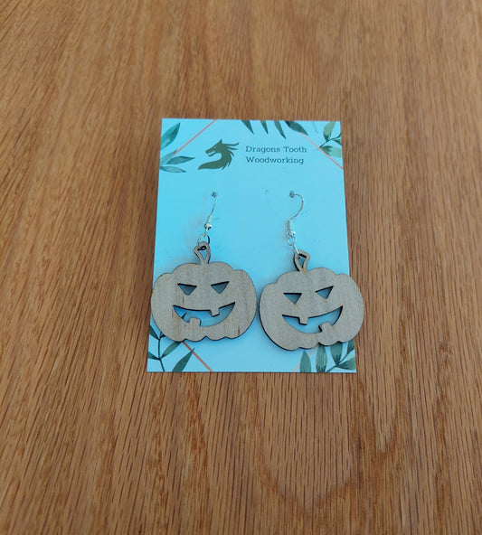 A front view of the festive jack-o'-lantern earrings crafted from light, bright blonde solid Maple wood, displayed on an earring card.