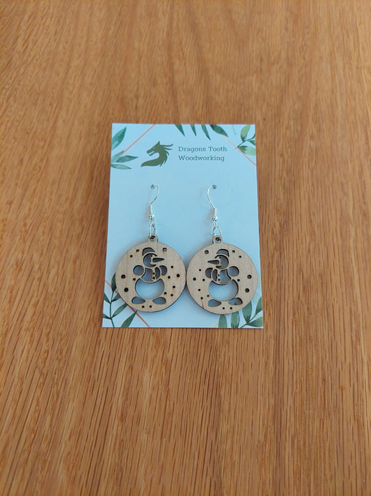 A front view of the seasonal snowman earrings crafted from light, bright blonde solid Maple wood, displayed on an earring card.