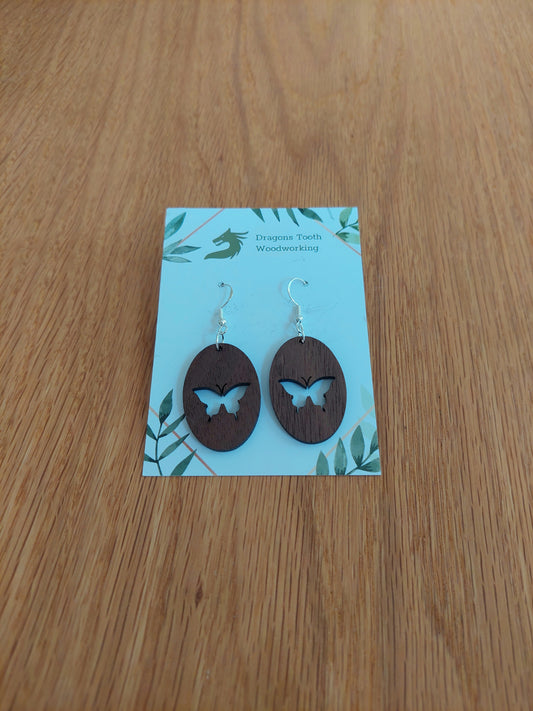 A front view of the butterfly earrings crafted from rich, deep chocolate-brown solid Walnut wood, displayed on an earring card.