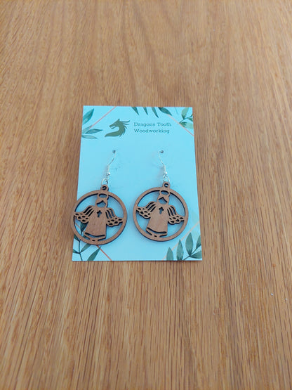 A pair of warm colored cherry wood angel earrings displayed with silver hooks on a card with the brand name 'Dragon's Tooth Woodworking'.