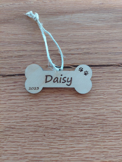 Custom engraved dog bone Christmas ornament made of birch wood with red ribbon, personalized with pet’s name for holiday decor.
