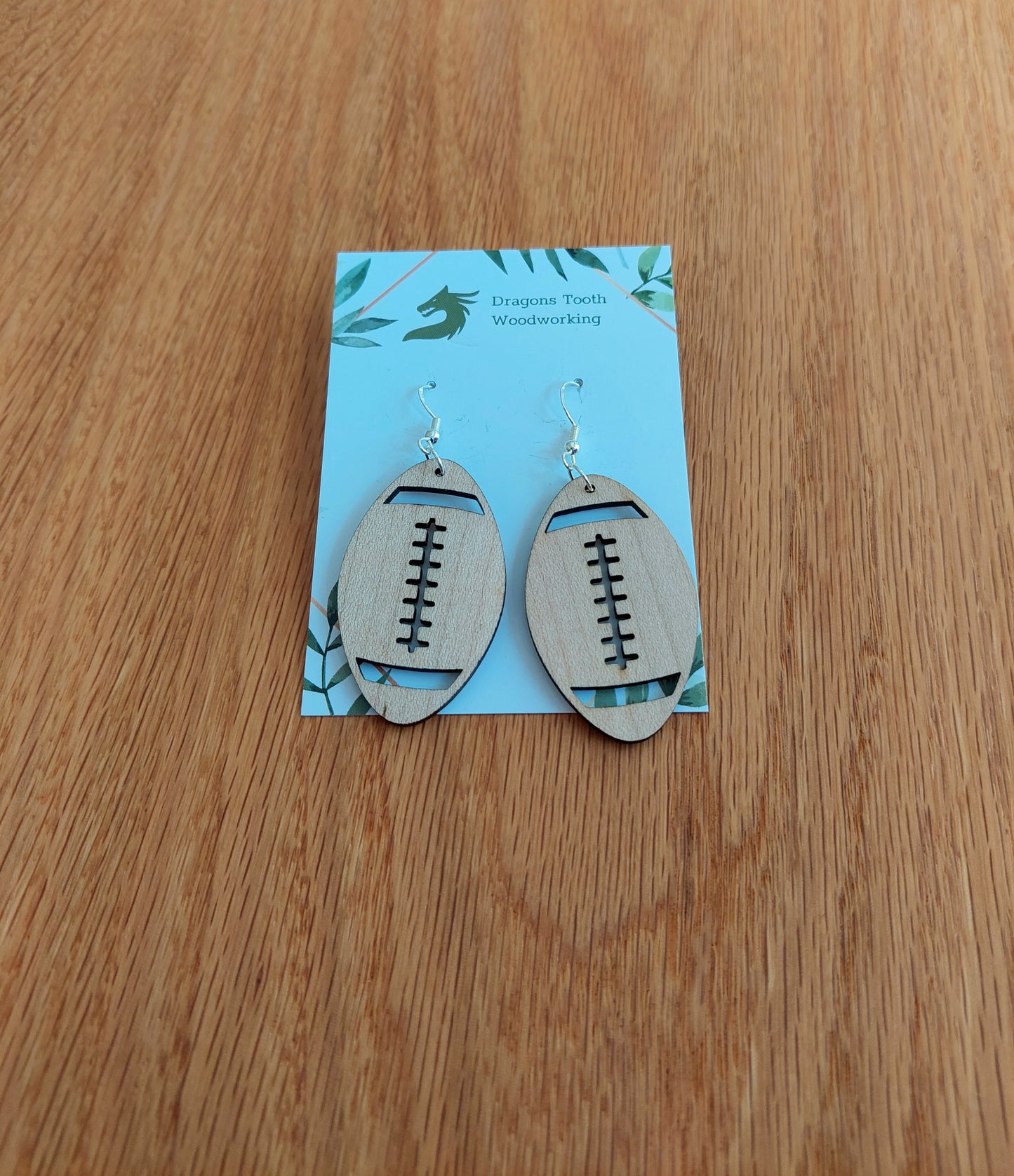 Handcrafted wooden football earrings made from natural maple, cherry, oak, or walnut, featuring hypoallergenic sterling silver-plated hooks — lightweight and sporty accessory for football fans
