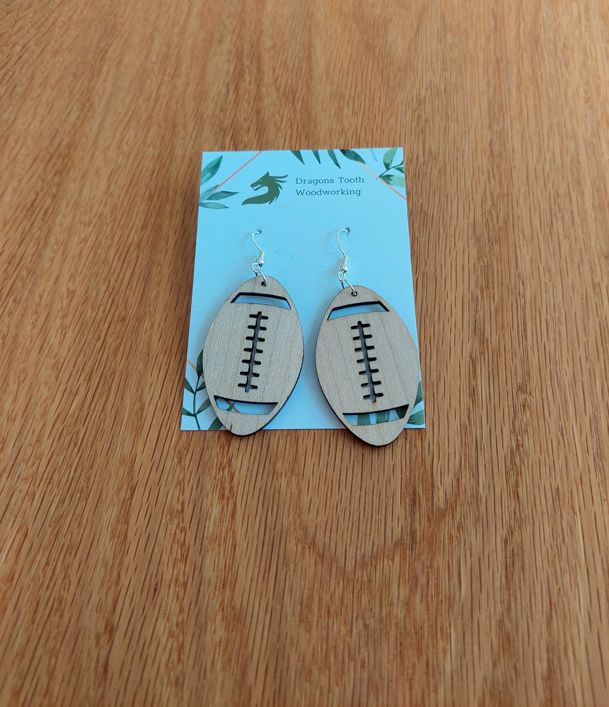 Handcrafted wooden football earrings made from natural maple, cherry, oak, or walnut, featuring hypoallergenic sterling silver-plated hooks — lightweight and sporty accessory for football fans