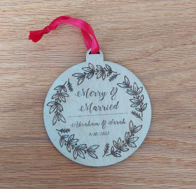 Personalized “Merry and Married” Christmas ornament made of engraved birch wood with red ribbon, celebrating a couple’s first holiday season together.