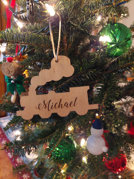 Engraved wooden train Christmas ornament made of birch wood with red ribbon, personalized for kids or train lovers.