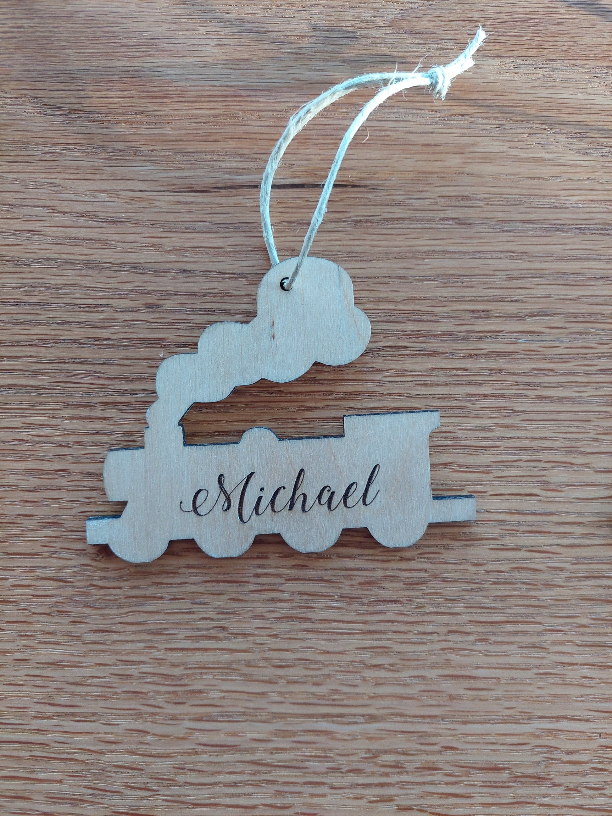 Engraved wooden train Christmas ornament made of birch wood with red ribbon, personalized for kids or train lovers.