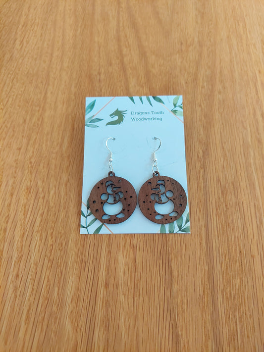 A pair of snowman-shaped earrings made from natural black walnut, displayed on a card