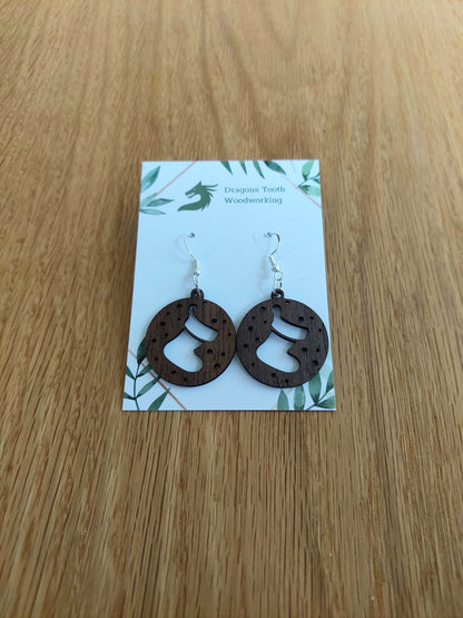 A pair of natural wood earrings featuring Christmas Stockings with hypoallergenic sterling silver plated hooks, displayed on a white card with 'Dragon's Tooth Woodworking' branding.