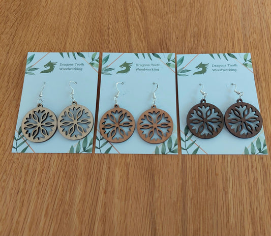 An alternate view displaying the open-cut snowflake earrings in three available wood types: light Maple, warm Cherry, and deep Walnut.