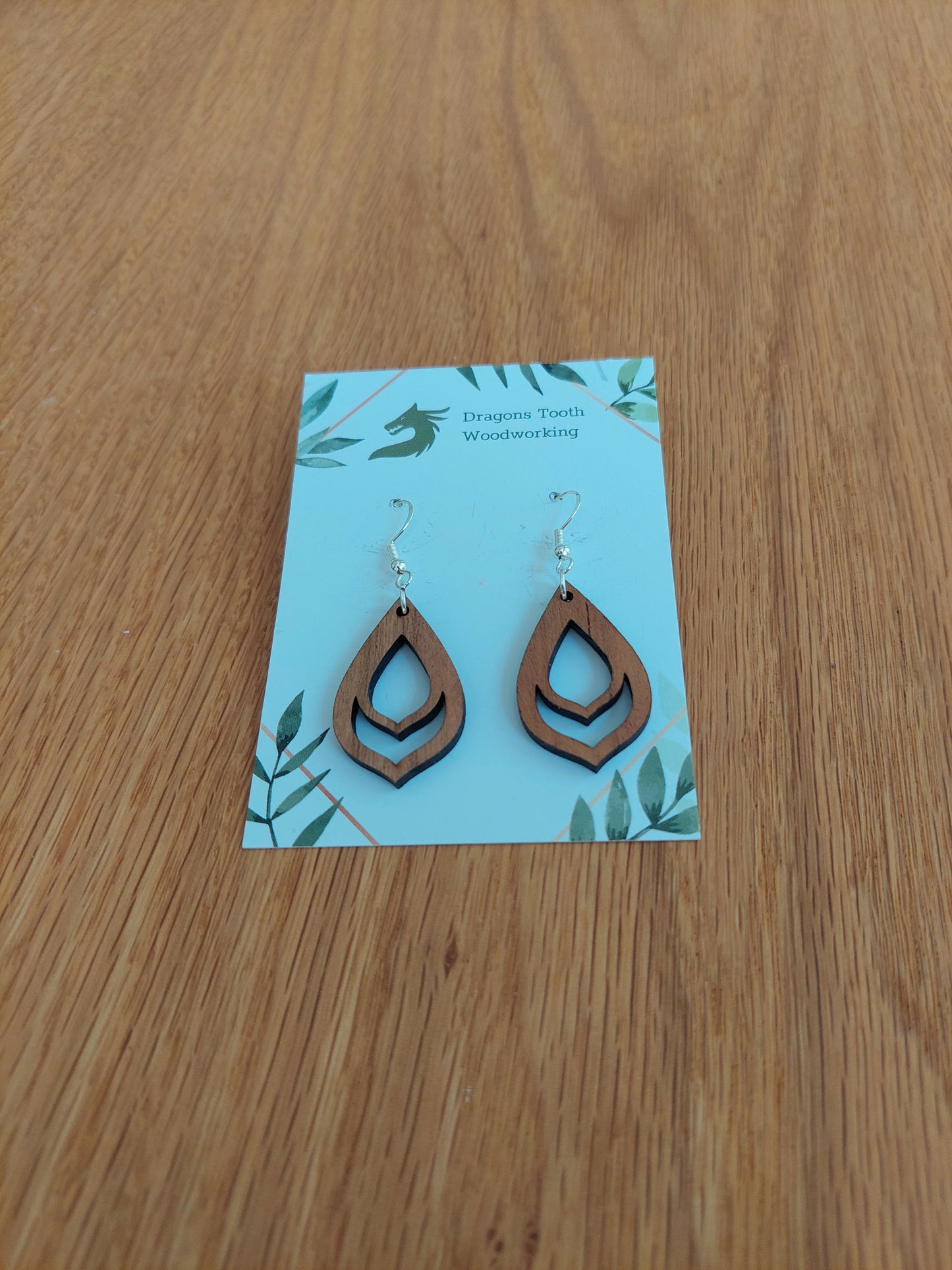 Front view of a pair of cherry wood budding flower bulb dangle earrings displayed on a rustic earring card.