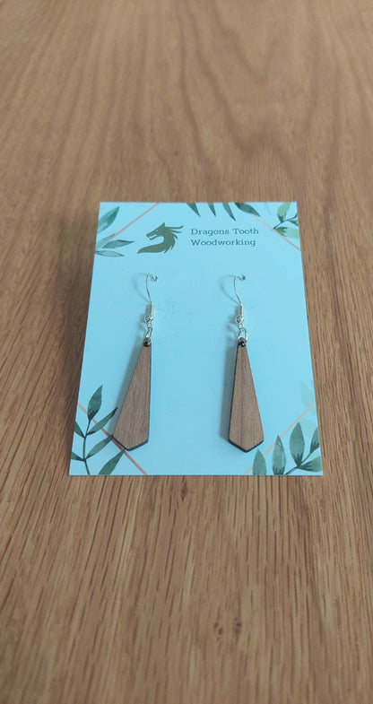 A front view of the minimalist tie silhouette earrings crafted from warm, traditional caramel-toned solid Cherry wood, displayed on an earring card.