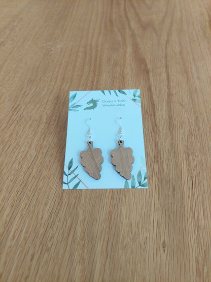 A front view of the grape cluster earrings crafted from warm, traditional caramel-toned solid Cherry wood, displayed on an earring card.