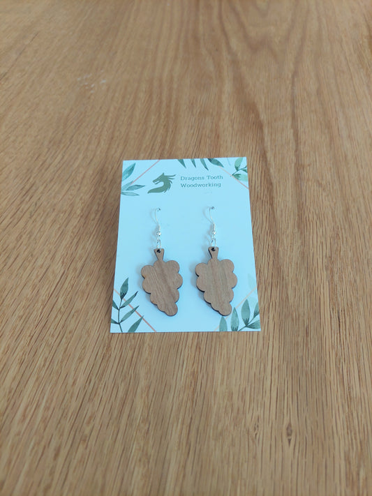 A front view of the grape cluster earrings crafted from warm, traditional caramel-toned solid Cherry wood, displayed on an earring card.