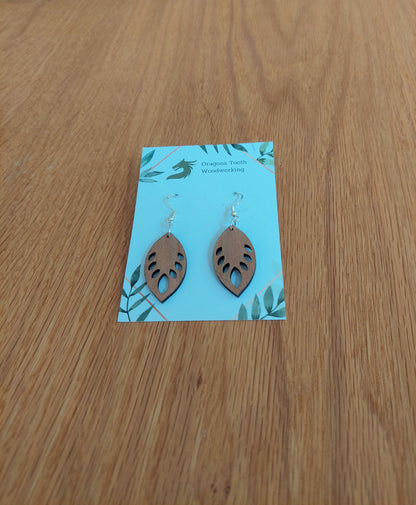 A front view of the monstera leaf earrings crafted from warm, traditional caramel-toned solid Cherry wood, displayed on an earring card.