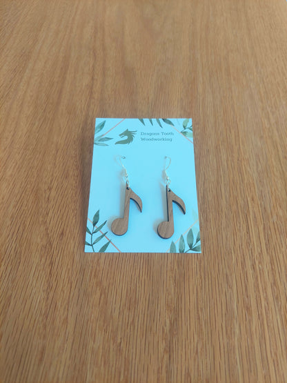 A front view of the circular music note earrings crafted from warm, traditional caramel-toned solid Cherry wood, displayed on an earring card.