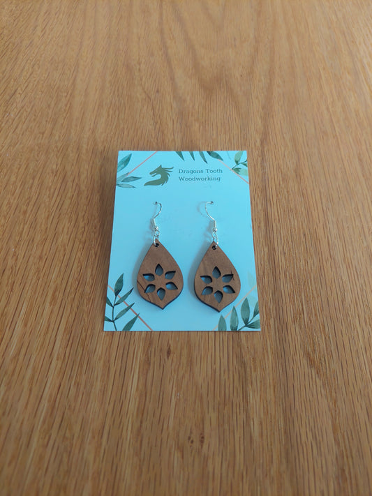 A front view of the minimalist star cutout earrings crafted from warm, traditional caramel-toned solid Cherry wood, displayed on an earring card.