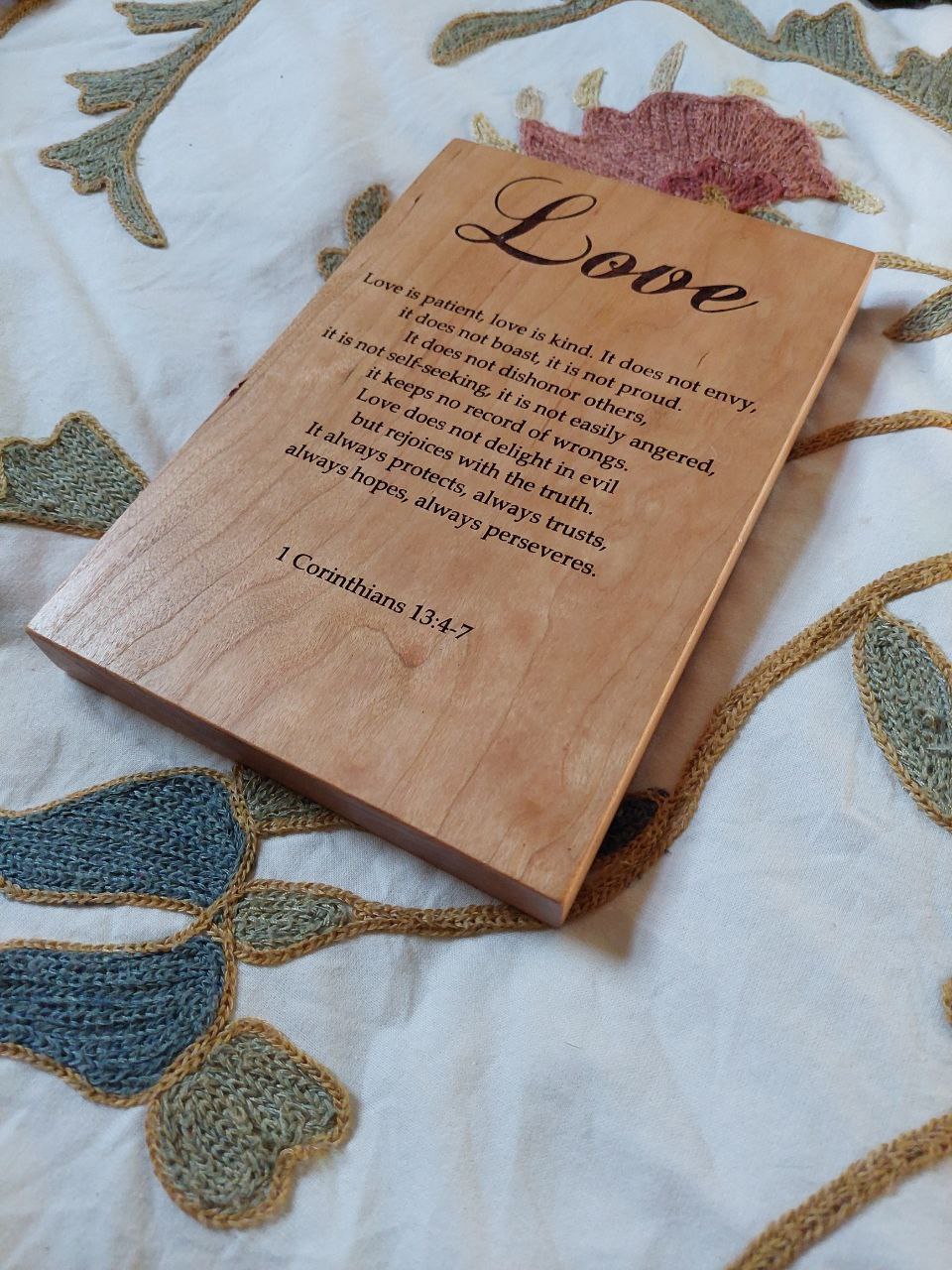 Angled close-up showing the deep, precise engraving details on a cherry wood Love Chapter plaque.
