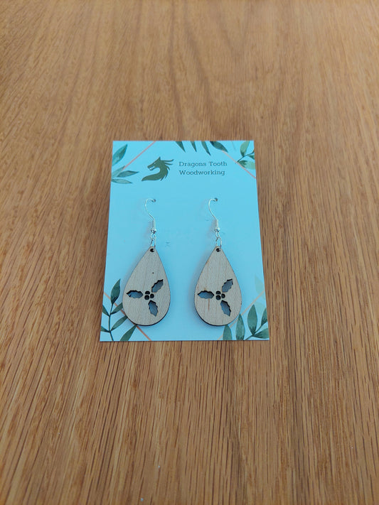 Front view of a pair of maple wood holly cluster teardrop dangle earrings on an earring display card