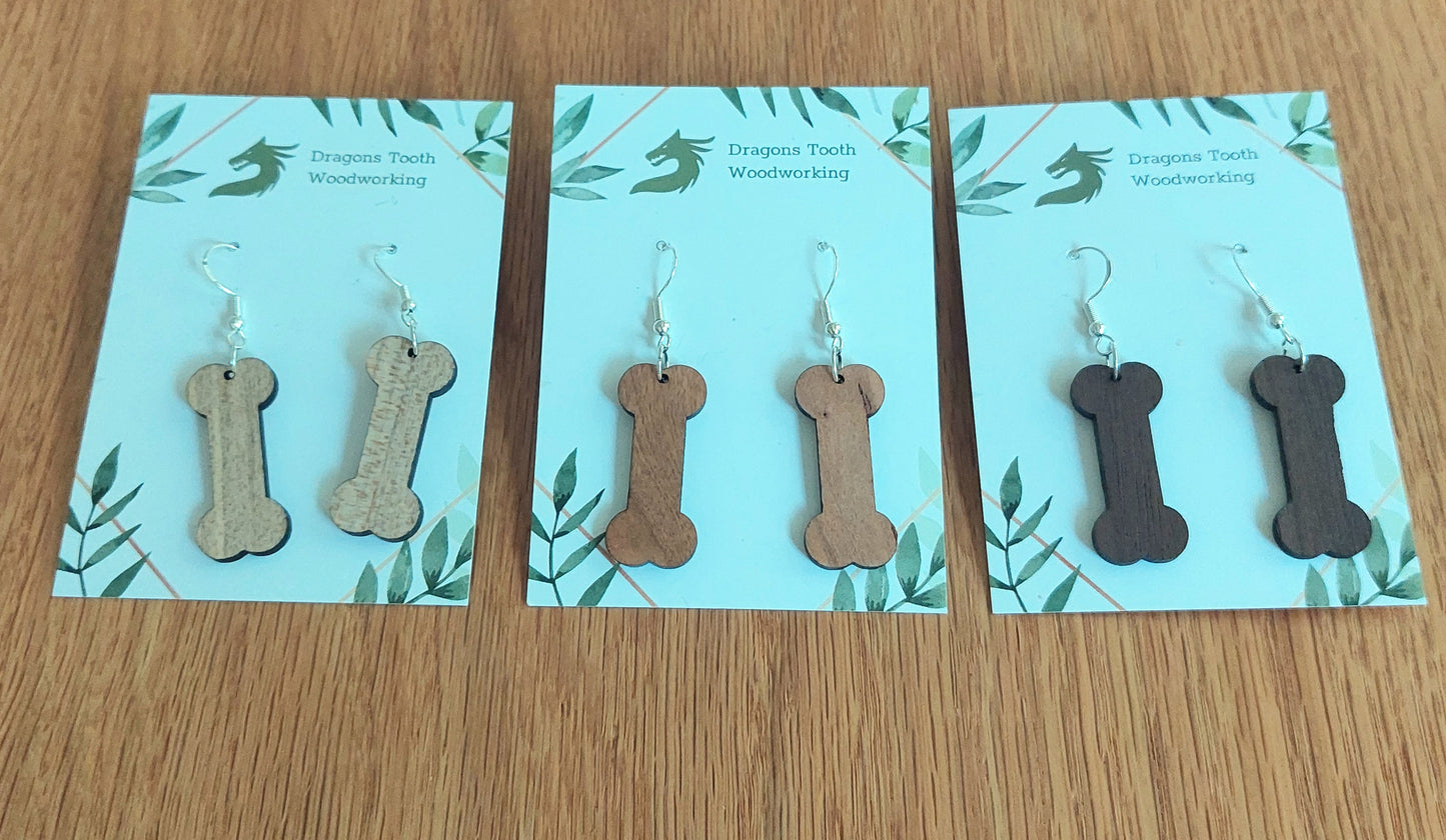 A beautiful lineup of handcrafted wooden dog bone dangle earrings displayed in natural maple, cherry, and walnut hardwoods.