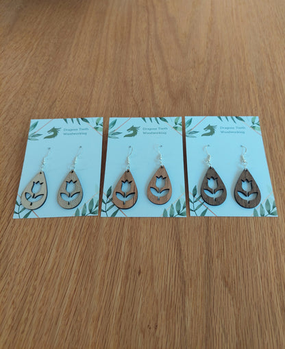 A beautiful collection of handcrafted wooden tulip flower dangle earrings displayed together in natural cherry, maple, and walnut hardwood finishes.