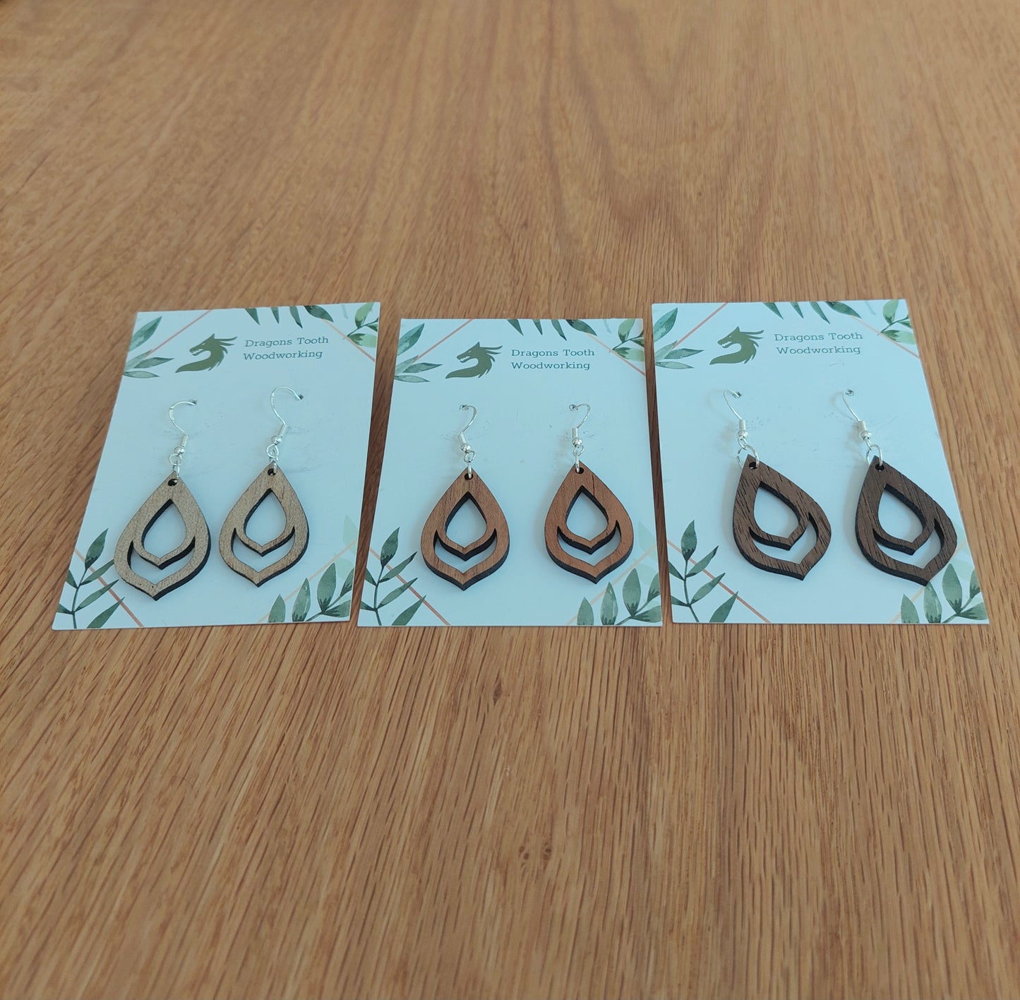 An alternate view displaying the budding flower bulb earrings in three available wood types: light Maple, warm Cherry, and deep Walnut.