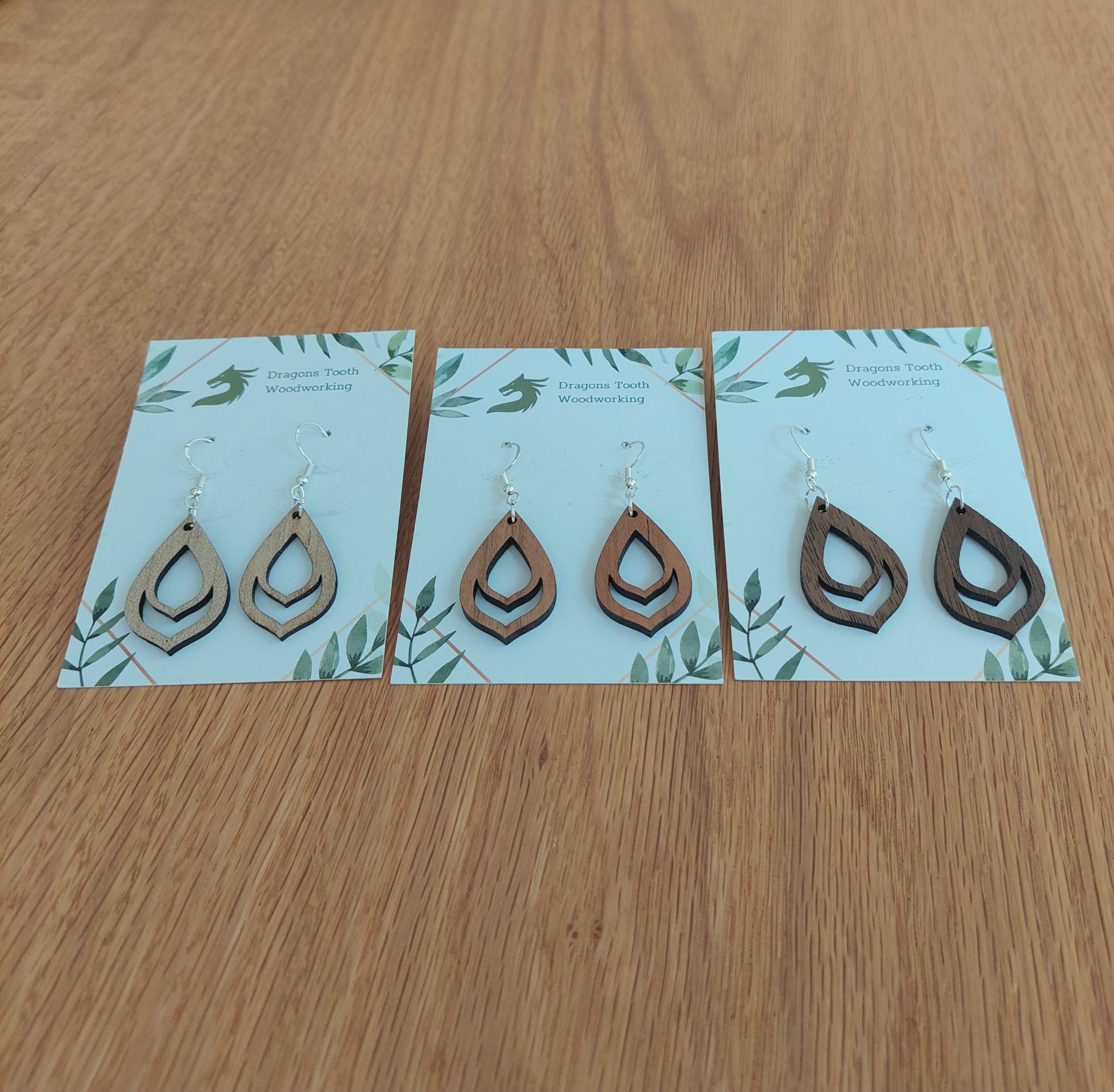 An alternate view displaying the budding flower bulb earrings in three available wood types: light Maple, warm Cherry, and deep Walnut.