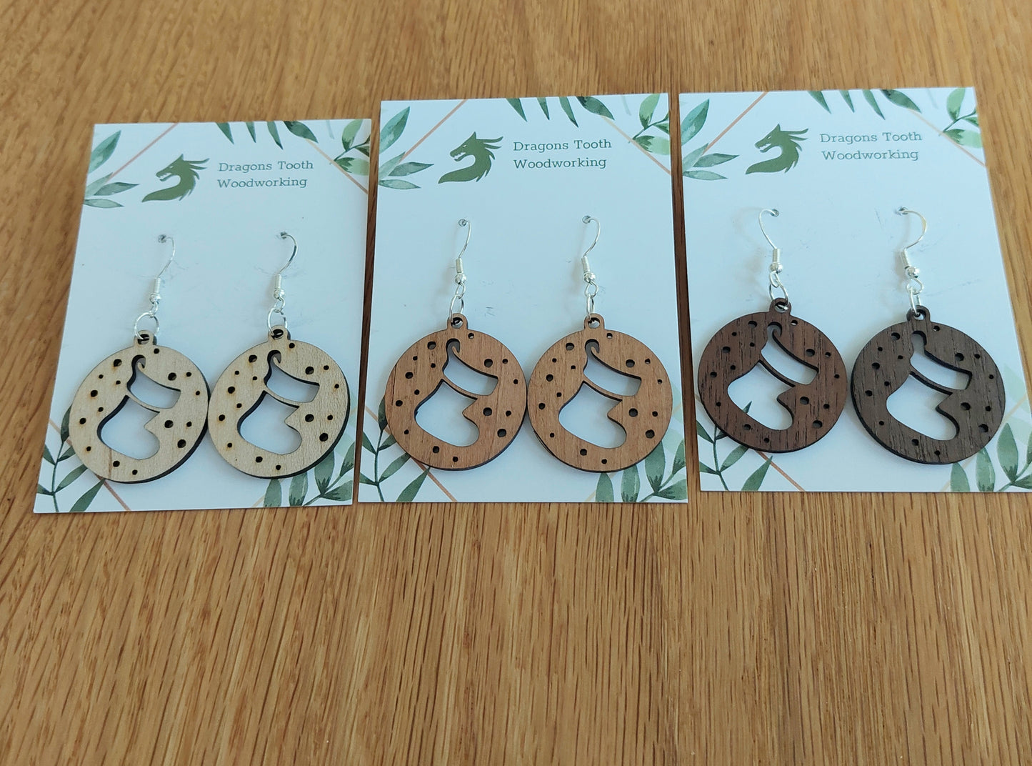 An alternate view displaying the Christmas stocking earrings in three available wood types: light Maple, warm Cherry, and deep Walnut.
