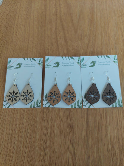 An alternate view displaying the large snowflake teardrop earrings in three available wood types: light Maple, warm Cherry, and deep Walnut.