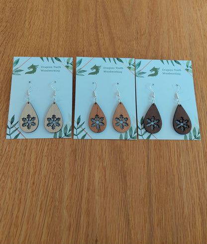 An alternate view displaying the snowflake teardrop earrings in three available wood types: light Maple, warm Cherry, and deep Walnut.