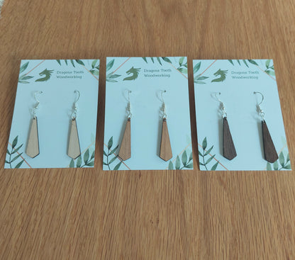 An alternate view displaying the tie silhouette geometric dangle earrings in three available wood types: light Maple, warm Cherry, and deep Walnut.