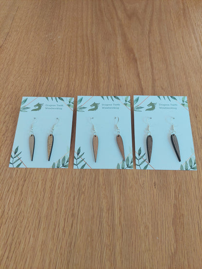An alternate view displaying the pointed geometric dangle earrings in three available wood types: light Maple, warm Cherry, and deep Walnut.
