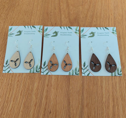 An alternate view displaying the holly cluster teardrop earrings in three available wood types: light Maple, warm Cherry, and deep Walnut.