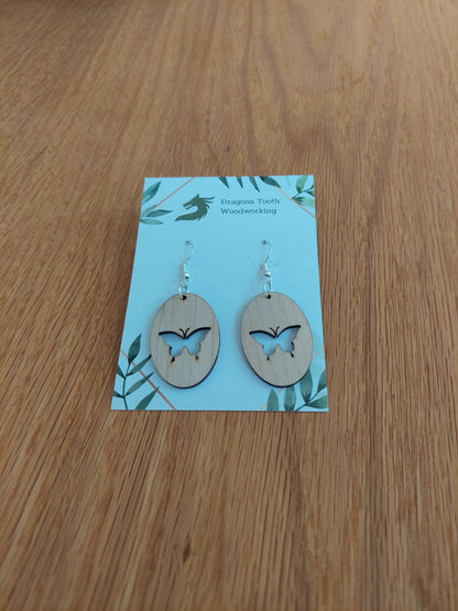 A front view of the butterfly earrings crafted from light, bright blonde solid Maple wood, displayed on an earring card.