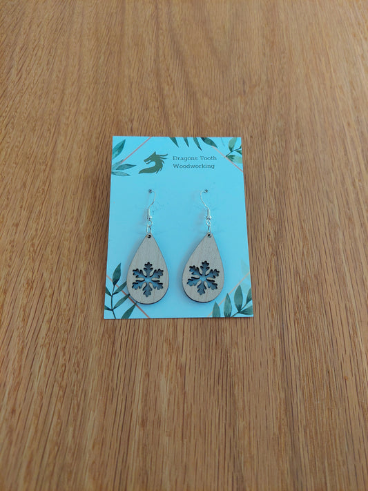 A front view of the snowflake teardrop earrings crafted from light, bright blonde solid Maple wood, displayed on an earring card.