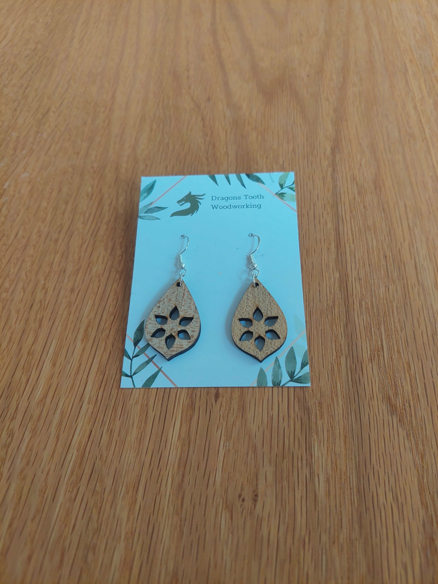 A front view of the minimalist star cutout earrings crafted from light, bright blonde solid Maple wood, displayed on an earring card.