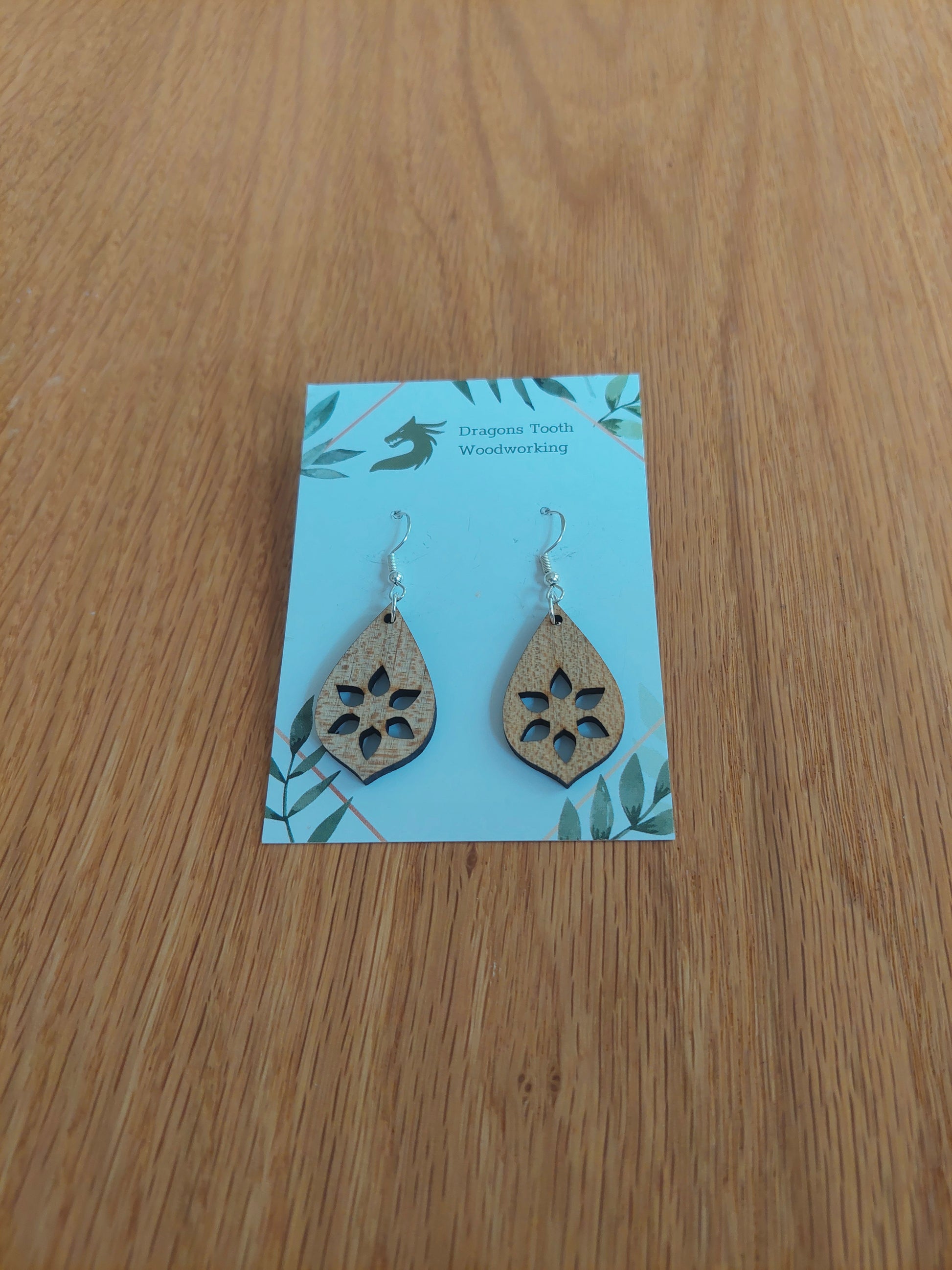 A front view of the minimalist star cutout earrings crafted from light, bright blonde solid Maple wood, displayed on an earring card.