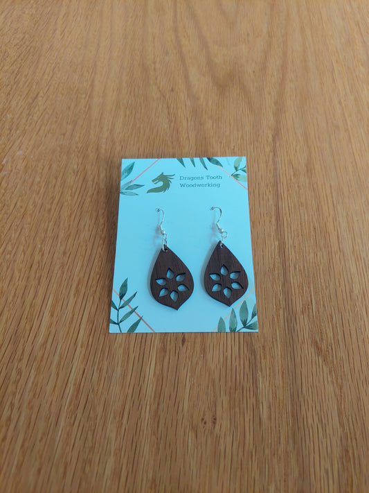 A front view of the minimalist star cutout earrings crafted from rich, deep chocolate-brown solid Walnut wood, displayed on an earring card.