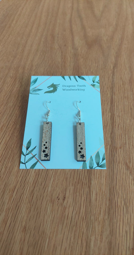 Front view of a pair of maple wood minimalist star shower geometric dangle earrings displayed on a rustic earring card.