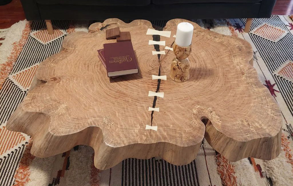 Wooden endgrain or cookie coffee table with live edges featuring dark epoxy fill and white holly duchmen or bowties to stabilize the checking.
