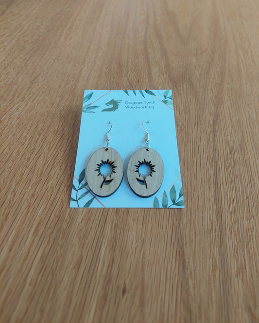 A front view of the aster flower earrings crafted from light, bright blonde solid Maple wood, displayed on an earring card