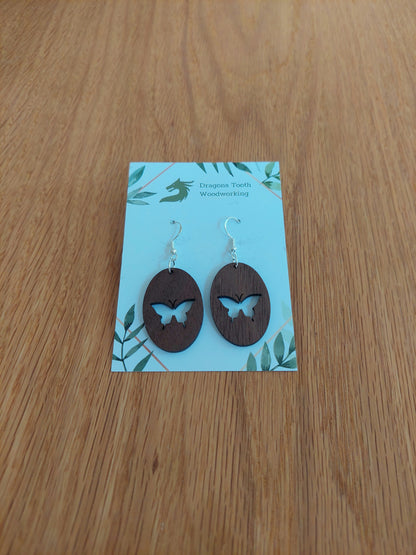 A front view of the butterfly earrings crafted from rich, deep chocolate-brown solid Walnut wood, displayed on an earring card.
