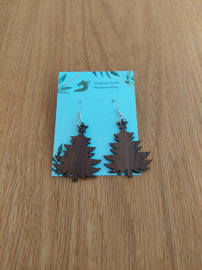 A front view of the Christmas tree earrings crafted from rich, deep chocolate-brown solid Walnut wood, displayed on an earring card.