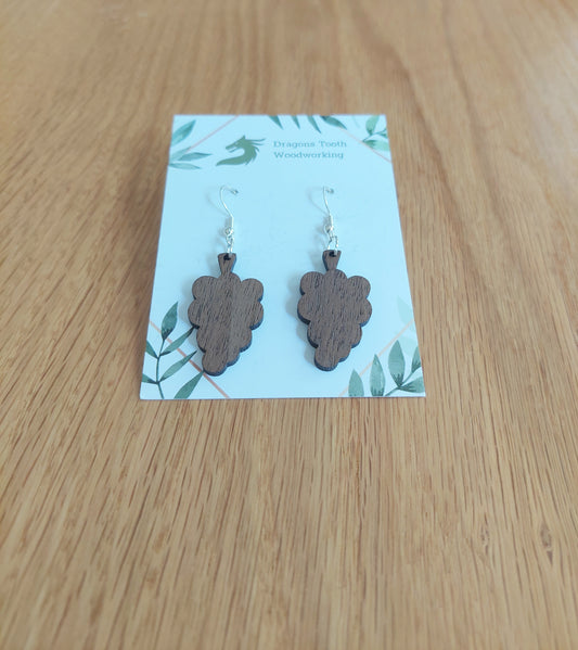 A front view of the grape cluster earrings crafted from rich, deep chocolate-brown solid Walnut wood, displayed on an earring card.