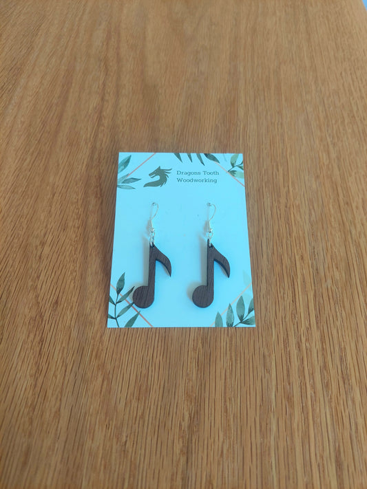 A front view of the circular music note earrings crafted from rich, deep chocolate-brown solid Walnut wood, displayed on an earring card.