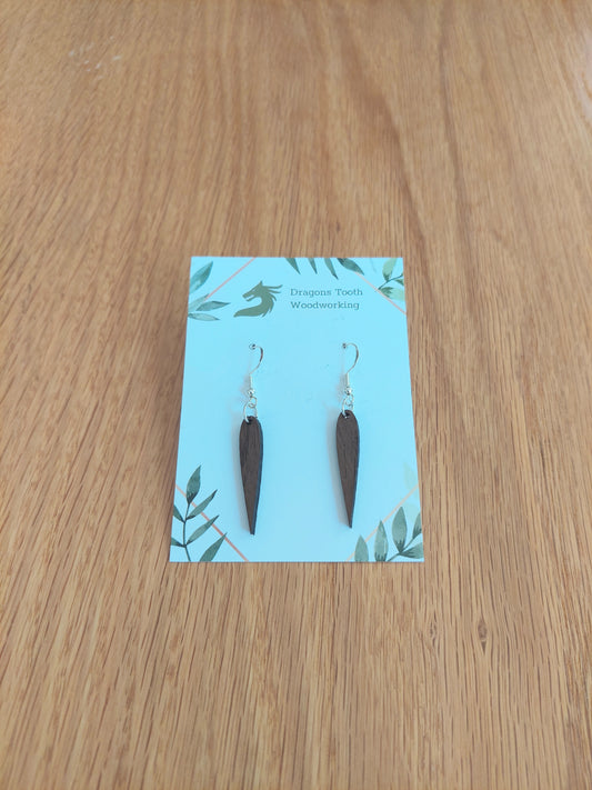A front view of the minimalist pointed geometric earrings crafted from rich, deep chocolate-brown solid Walnut wood, displayed on an earring card.